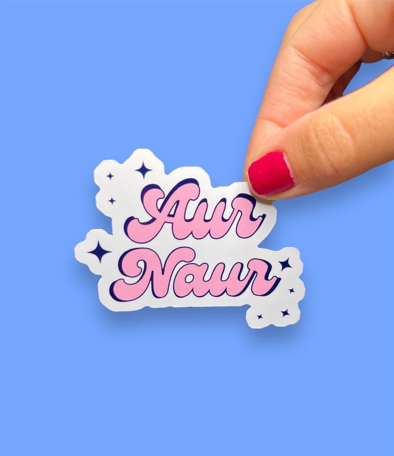 Peut inclure: Un autocollant blanc avec un lettrage rose et bleu qui dit "Aur Naur" avec de petites &eacute;toiles blanches autour du texte.