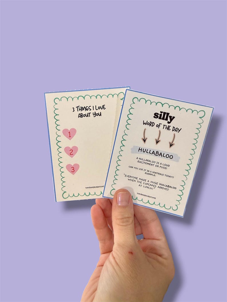 Może przedstawiać: Dwie karty trzymane w dłoni, z zabawnymi tekstami i wzorami. Jedna karta głosi "3 THINGS I LOVE ABOUT YOU" z ikonami serca. Druga karta m&oacute;wi "silly WORD OF THE DAY" ze słowem "HULLABALOO" i jego definicją.