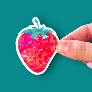 May include: A red and green iridescent sticker of a strawberry. The strawberry is made up of small triangles that create a mosaic effect.