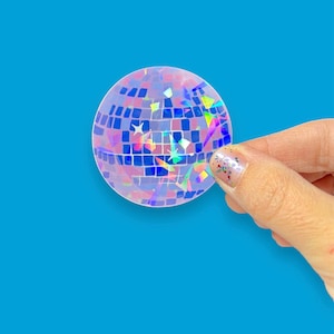 May include: A clear iridescent sticker with a disco ball design. The sticker has a holographic finish with a variety of colors, including blue, pink, and green.