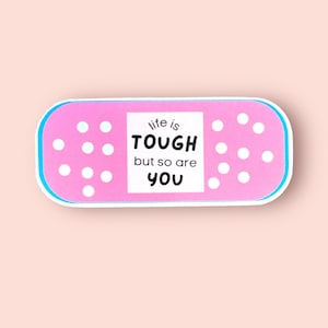 May include: Pink band-aid sticker with white dots and the text "life is tough but so are you".