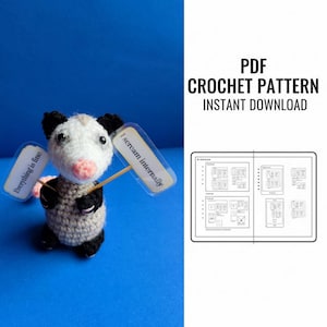 May include: A crocheted opossum with a white head, gray body, and pink tail holds two signs that read "Everything is fine" and "I scream internally." The image also includes a PDF crochet pattern with diagrams.
