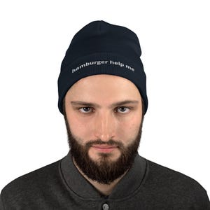 May include: A navy blue beanie with the text "hamburger help me" embroidered in white on the front.