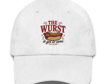 Könnte beinhalten: Eine weiße Baseballkappe mit einer Grafik eines traurigen Hotdogs mit gelbem Senf. Der Text über dem Hotdog lautet THE WURST in Rot, und der Text darunter lautet is yet to come in Schwarz, ergänzt durch kleine dekorative Linien und Sternakzente.