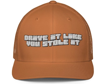 Könnte beinhalten: Eine einfarbige orangefarbene Trucker-Cap mit Netzrücken und strukturiertem Vorderteil. Auf der Vorderseite befindet sich der gestickte weiße Schriftzug "DRIVE IT LIKE YOU STOLE IT" in einer fetten, blockartigen Pixel-Schrift mit schwarzer Umrandung.