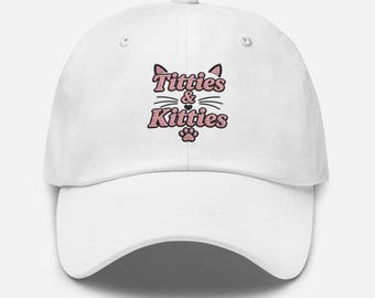Könnte beinhalten: Eine weiße Baseballkappe mit einer gestickten Grafik aus Katzenohren, Schnurrhaaren und einem Pfotenabdruck. Der Text "Titties & Kitties" ist mittig in rosa und schwarz gestreiften Buchstaben zwischen den Ohren und der Pfote platziert.