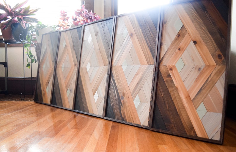 Puede incluir: Una pieza de arte de pared hecha de madera con un patr&oacute;n geom&eacute;trico. La madera est&aacute; te&ntilde;ida en tonos de marr&oacute;n, gris y blanco. La pieza est&aacute; compuesta por cuatro paneles.
