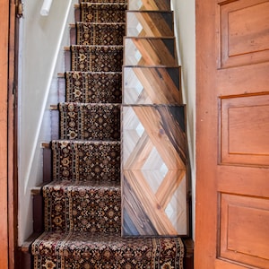 Puede incluir: Una escalera de madera con una alfombra de corredor estampada y un dise&ntilde;o de panel de madera geom&eacute;trico en la pared. El panel de madera est&aacute; hecho de diferentes tonos de madera marr&oacute;n.