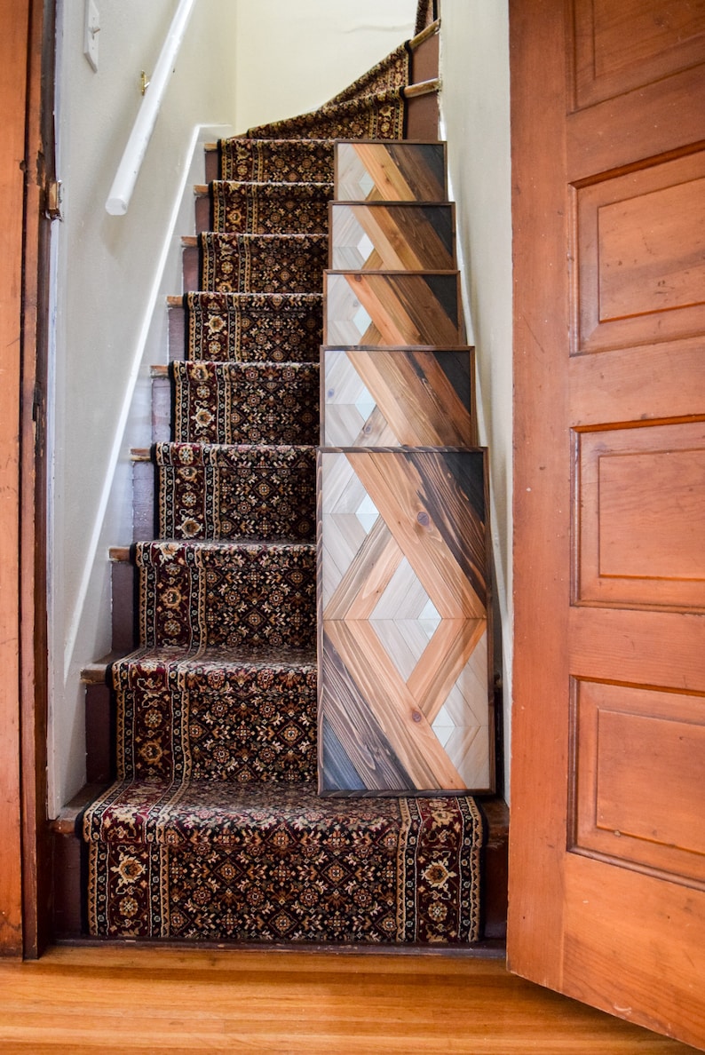 Puede incluir: Una escalera de madera con una alfombra de corredor estampada y un dise&ntilde;o de panel de madera geom&eacute;trico en la pared. El panel de madera est&aacute; hecho de diferentes tonos de madera marr&oacute;n.