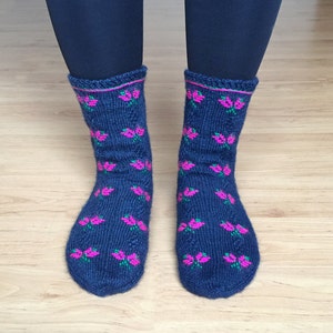 May include: A pair of blue knitted socks with a pink and green floral pattern.