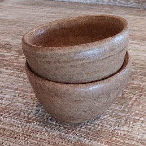 May include: Two stacked brown ceramic bowls with a speckled glaze.