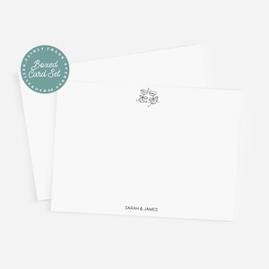 May include: A boxed card set with a white card and envelope. The card has a black floral design in the upper right corner and the names "Sarah & James" printed at the bottom. A teal sticker with the words "Boxed Card Set" is on the upper left.