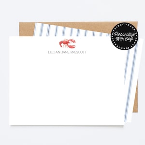 Op de afbeelding: Wit briefpapier met een rode kreeftillustratie en de naam "Lillian Jane Prescott" gedrukt in een schreefletter. Het briefpapier wordt gecombineerd met een gestreepte blauw-witte envelop en een bruine kraftpapieren envelop.