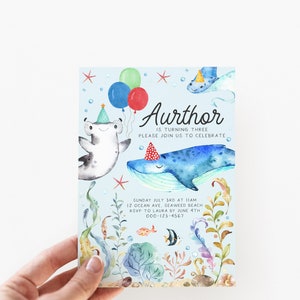 May include: A blue and white invitation card with a watercolor illustration of a whale, a hammerhead shark, and a starfish. The text on the card reads "Aurthor is turning three. Please join us to celebrate. Sunday July 3rd at 11am. 12 Ocean Ave, Seaweed Beach. RSVP to Laura by June 4th. 000-123-4567."