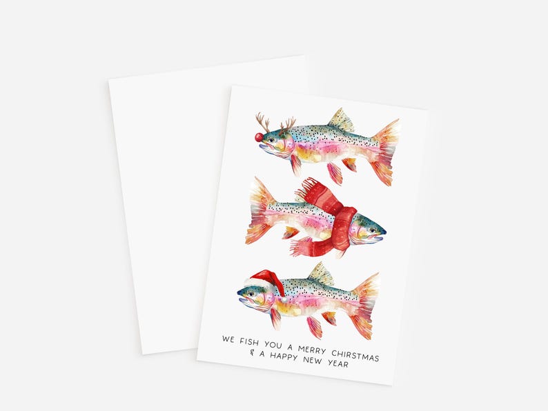 May include: A set of two white greeting cards. The front card features three watercolor fish, each adorned with festive holiday accessories: antlers, a scarf, and a Santa hat. The text reads, "We fish you a Merry Chirstmas & a Happy New Year."