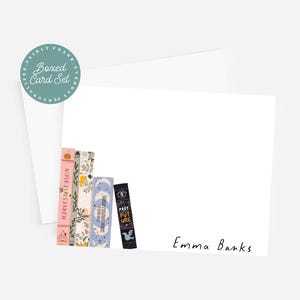 May include: A boxed card set with a white background. The set includes a stack of decorative cards with book-themed designs and the words "Harvest Season," "Past Future," and "Daily Constellations." The name "Emma Banks" is written in cursive.