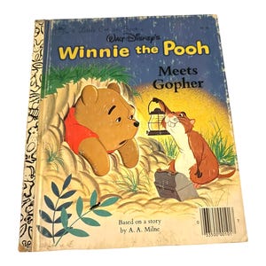 Könnte beinhalten: Ein Vintage-Kinderbuch mit dem Titel "Winnie the Pooh Meets Gopher". Das Cover zeigt eine Illustration von Winnie the Pooh in einem roten Hemd und Gopher mit einer Laterne. Das Buch basiert auf einer Geschichte von A. A. Milne.