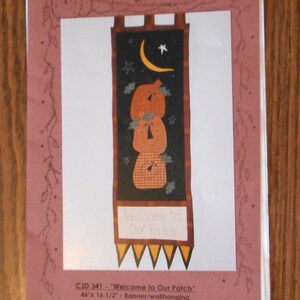 May include: A printed pattern for a banner or wall hanging. The design features three stacked pumpkins, a crescent moon, and the text "Welcome to Our Patch." The banner measures 46 inches by 16.5 inches.