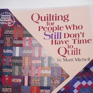 May include: A book cover titled "Quilting for People Who Still Don't Have Time to Quilt" by Marti Michell. The cover features colorful quilt patterns in various designs and colors, including red, blue, and purple. The American School of Needlework logo is in the upper left corner.