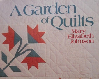 Könnte beinhalten: Buchcover von "A Garden of Quilts" von Mary Elizabeth Johnson. Das Design zeigt ein gestepptes Muster mit roten und grünen Blumenmotiven auf cremefarbenem Hintergrund. Der Titel ist türkis und der Name des Autors ist rot.