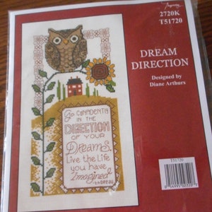 May include: Cross stitch pattern featuring an owl, a house, and a sunflower with the text "Go confidently in the direction of your dreams. Live the life you have imagined." - Thoreau. The pattern is titled "Dream Direction" and designed by Diane Arthurs.