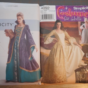 May include: Two Simplicity sewing patterns for adult costumes. The pattern on the left is for a purple and teal gown with gold trim and is labeled "S9166". The pattern on the right is for a white and gold gown with lace trim and is labeled "4092".