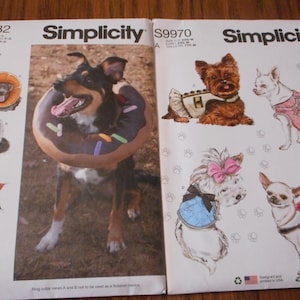May include: Two Simplicity sewing pattern envelopes featuring dog costumes and accessories. One envelope shows a dog wearing a donut-shaped collar. The other shows illustrations of dogs in various outfits, including a dress and a harness.
