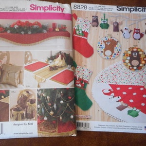 Op de afbeelding: Twee Simplicity naaipatronen. Eén toont kersttafeldecoraties, waaronder een rode tafelloper met gouden franjes. De andere toont kerstsokken, ornamenten en een boomrok met feestelijke ontwerpen.