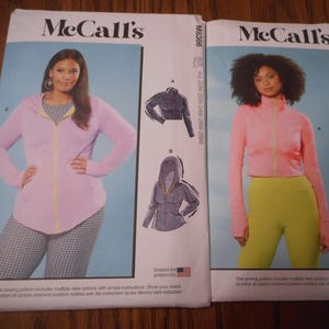 May include: Two McCall's sewing pattern envelopes. One features a woman in a pink zip-up hoodie and checkered pants. The other shows a woman in a pink zip-up jacket and yellow leggings. Both patterns include illustrations of jacket designs.