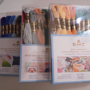 May include: Three packages of DMC embroidery floss. The packages are labeled "Holiday Decor", "Gold Collection", and "Anniversary". Each package contains 8.7 yards of floss and includes a small image of a finished embroidery project.