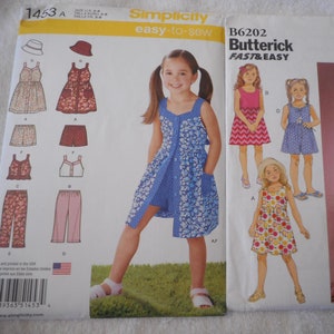 May include: Two sewing patterns for girls' dresses. The pattern on the left is Simplicity 1453 and includes a dress with a pocket and shorts. The pattern on the right is Butterick B6202 and includes a dress with a ruffle and a long dress.