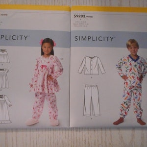 以下が含まれることがあります： Simplicityの裁縫パターンパッケージ2つ。左のパッケージは女の子用のパジャマで、S9204とラベル付けされています。右のパッケージは男の子用のパジャマで、S9203とラベル付けされています。