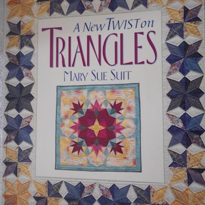 May include: A book titled "A New Twist on Triangles" by Mary Sue Suit. The cover features a quilt with a colourful star pattern in the centre and a border of blue and yellow stars.