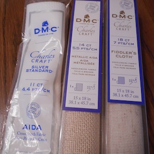 May include: Three DMC Charles Craft cross-stitch fabric packs. The packs contain Aida cloth, Metallic Aida, and Fiddler's Cloth. Fabric dimensions are 15 x 18 inches (38.1 x 45.7 cm).