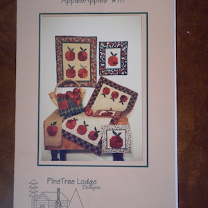 May include: A quilting pattern featuring red apples with a green stem and leaf. The pattern is called "ApplesApples #117" and is designed by PineTree Lodge Designs.