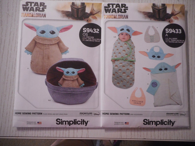 May include: Two Simplicity sewing patterns for making Star Wars Mandalorian baby items. The pattern on the left is for a plush toy and a soft space pram. The pattern on the right is for a baby swaddle, a hooded towel, and a bib. Both patterns feature the character Baby Yoda.