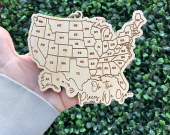 May include: Wooden ornament shaped like the United States of America with each state labeled. The ornament has the text "Oh The Places We Go..." at the bottom.
