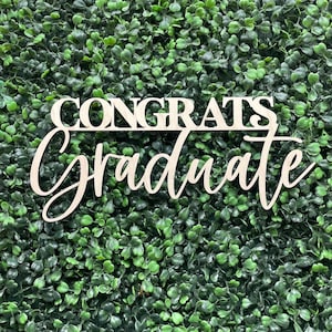 May include: Wooden sign with the words "Congrats Graduate" in white lettering against a green background.
