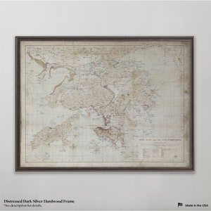 May include: A vintage map of Hong Kong and the New Territories, framed in a distressed dark silver hardwood frame. The map is printed on aged paper with a faded, cream-colored background.