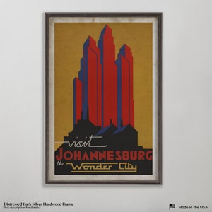 May include: A vintage travel poster with a distressed dark silver hardwood frame. The poster features a stylized image of a city skyline in red, blue, and black against a yellow background. The text on the poster reads "visit JOHANNESBURG the Wonder City".