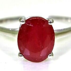 Può includere: Un anello d'argento con una grande pietra rossa di forma ovale.