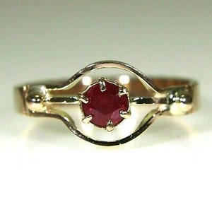 May include: A gold ring with a red ruby gemstone set in a delicate, open-work design.