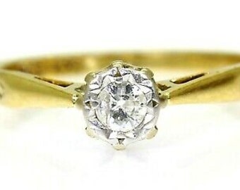 May include: A gold band ring with a single round diamond set in a prong setting. The diamond is surrounded by a delicate halo of smaller diamonds.