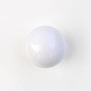 May include: A smooth, spherical object with a glossy white finish. The surface reflects light, creating a bright highlight on the upper portion of the sphere. The object is solid in color and features a perfectly round, uniform shape throughout.