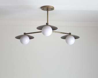 May include: A brass three-light chandelier with white globe shades and a geometric design.