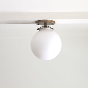 May include: A white globe ceiling light fixture with a brass finish.