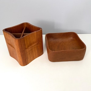 May include: Two wooden desk organizers. One is a tall, multi-compartment holder with a unique, curved shape. The other is a small, square bowl. Both are made of a warm, reddish-brown wood, showcasing the natural grain.