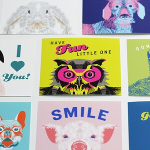 May include: Set of eight greeting cards featuring colorful illustrations of animals with text. The cards include a flamingo, a rabbit, a dog, an owl, a cat, a pig, a bulldog, and a zebra. The text on the cards includes "I love you!", "Have Fun Little One", "Don't Give Up", "Smile", "Have a Good Day", and "Hugs!"