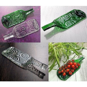 Könnte beinhalten: Vier Serviertabletts aus Glas, hergestellt aus recycelten Weinflaschen. Die Tabletts haben ein Spiralmuster und sind in verschiedenen Grüntönen gehalten. Ein Tablett ist mit roten Kirschtomaten gefüllt.