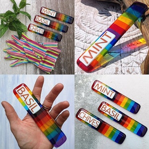 May include: Rainbow glass plant markers with the words "Mint", "Basil", and "Chives" written in white on each marker.